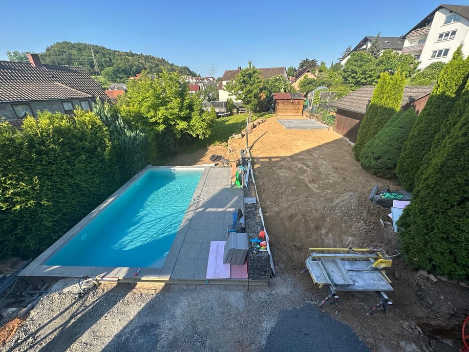 Fertiger Pool mit Terrassenplatten während der Gartengestaltung aus der Vogelperspektive